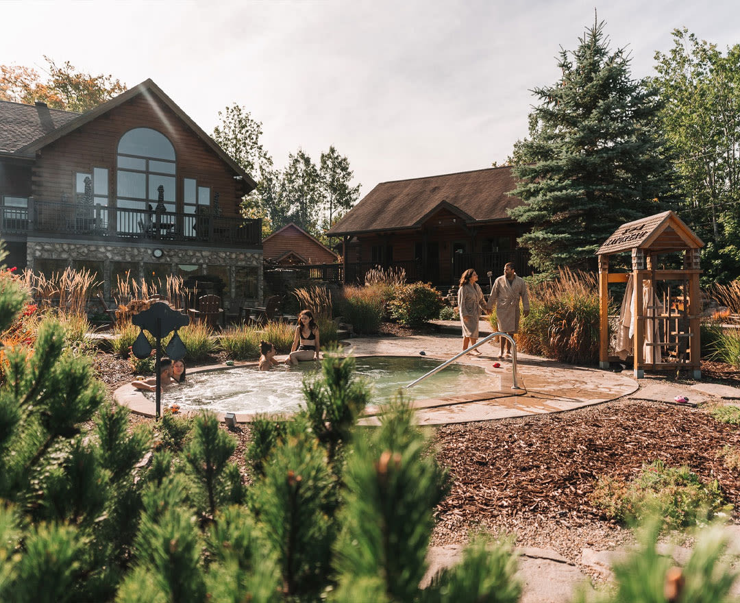 Natur'Eau Spa & Chalets: Un moment de détente absolue dans un spa extérieur, entouré d’une végétation aux chaleureuses couleurs automnales.