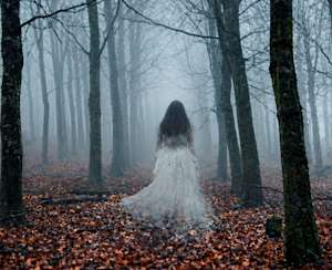 Mentaliste: Une mystérieuse silhouette vêtue de blanc avance dans une forêt brumeuse à l’atmosphère sombre et envoûtante.