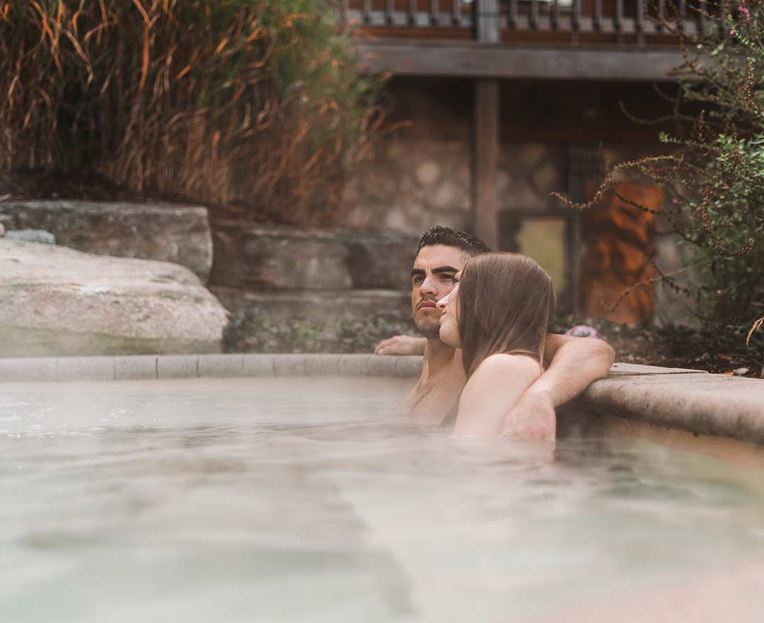 Natur'Eau Spa & Chalets: Un couple profite d’un moment de détente dans un bain chaud extérieur, entouré d’un décor naturel apaisant