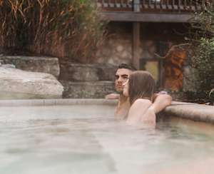Natur'Eau Spa & Chalets: Un couple profite d’un moment de détente dans un bain chaud extérieur, entouré d’un décor naturel apaisant.