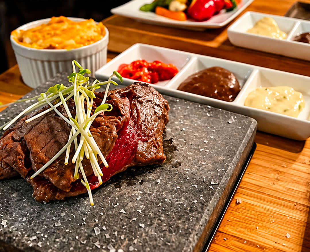 Tranches de viande grillée avec germes, légumes colorés et gratin de pommes de terre sur une table en bois.