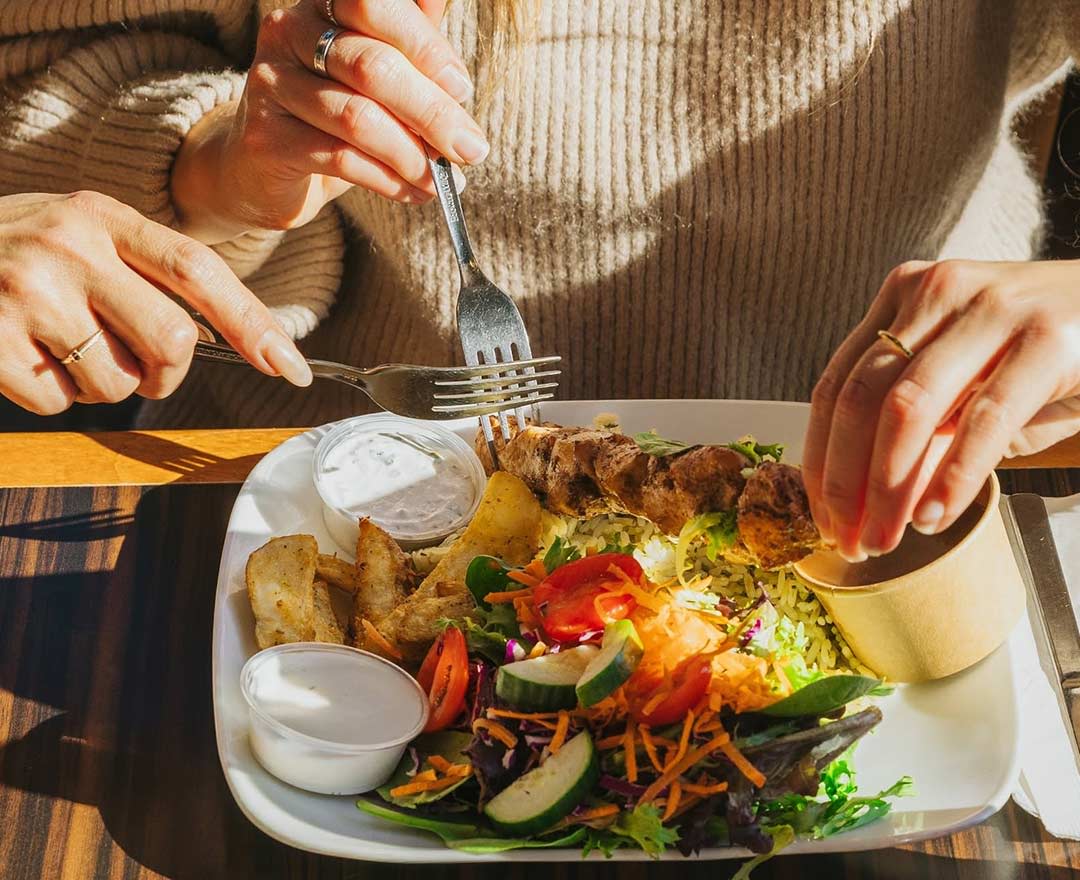 Une table bien remplie d'assiettes de spagetti, cuisse de poulet et frites, poitrine de poulet et frites, pépite de poulet et frites, une boisson gazeuse