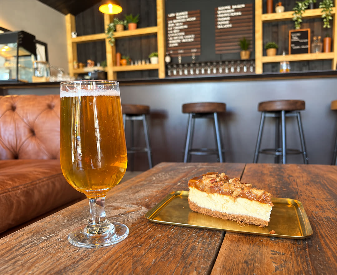Une bière dorée accompagnée d’une part de gâteau est servie dans une ambiance chaleureuse de microbrasserie.