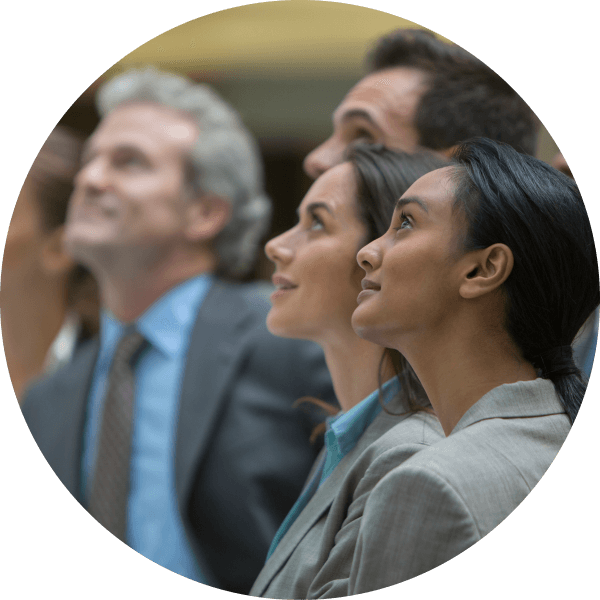 A group of four individuals look upwards. They are all dressed in professional attire, with suits and ties.