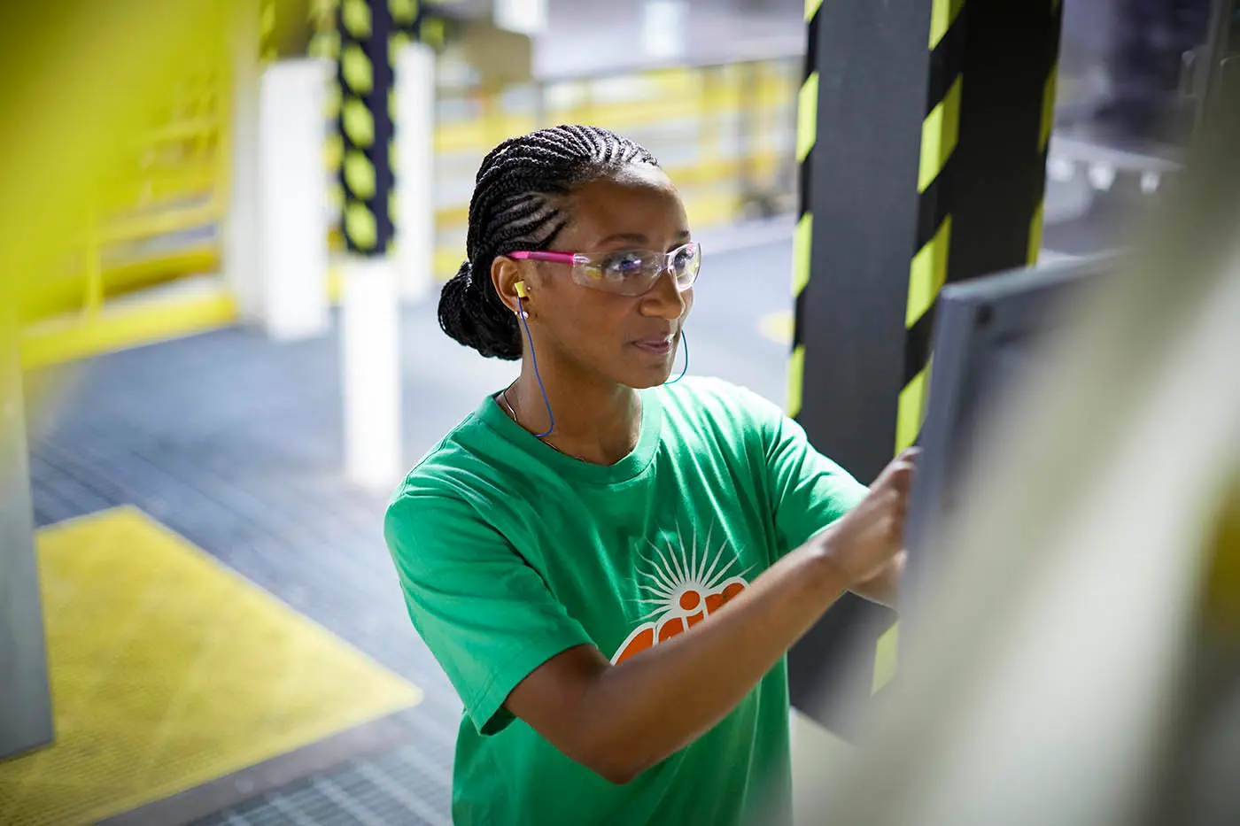 Woman wearing a green shirt with Gain logo in an manufacturing facility