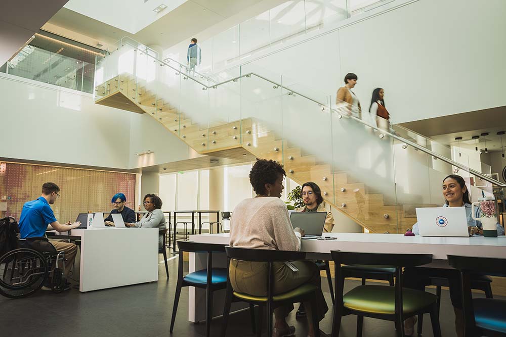 Several people sit together at various office work stations.