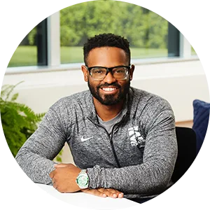 Man wearing a gray shirt, smiling and looking towards the camera