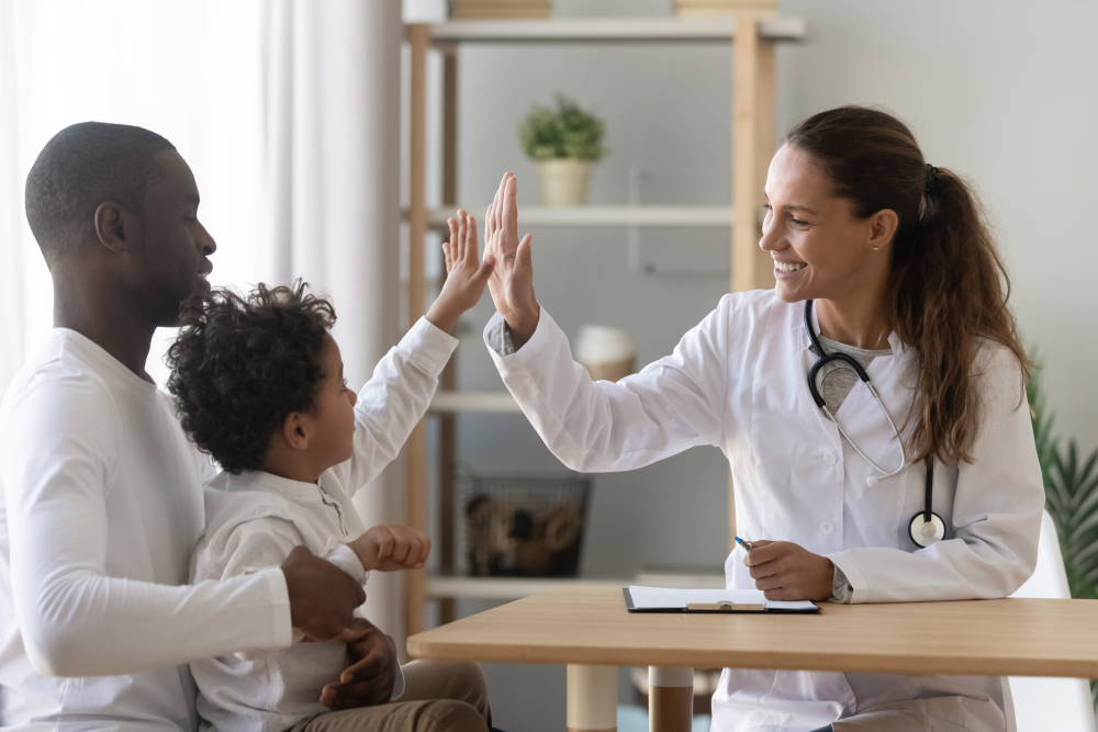Pediatrician and young child high-fiving.