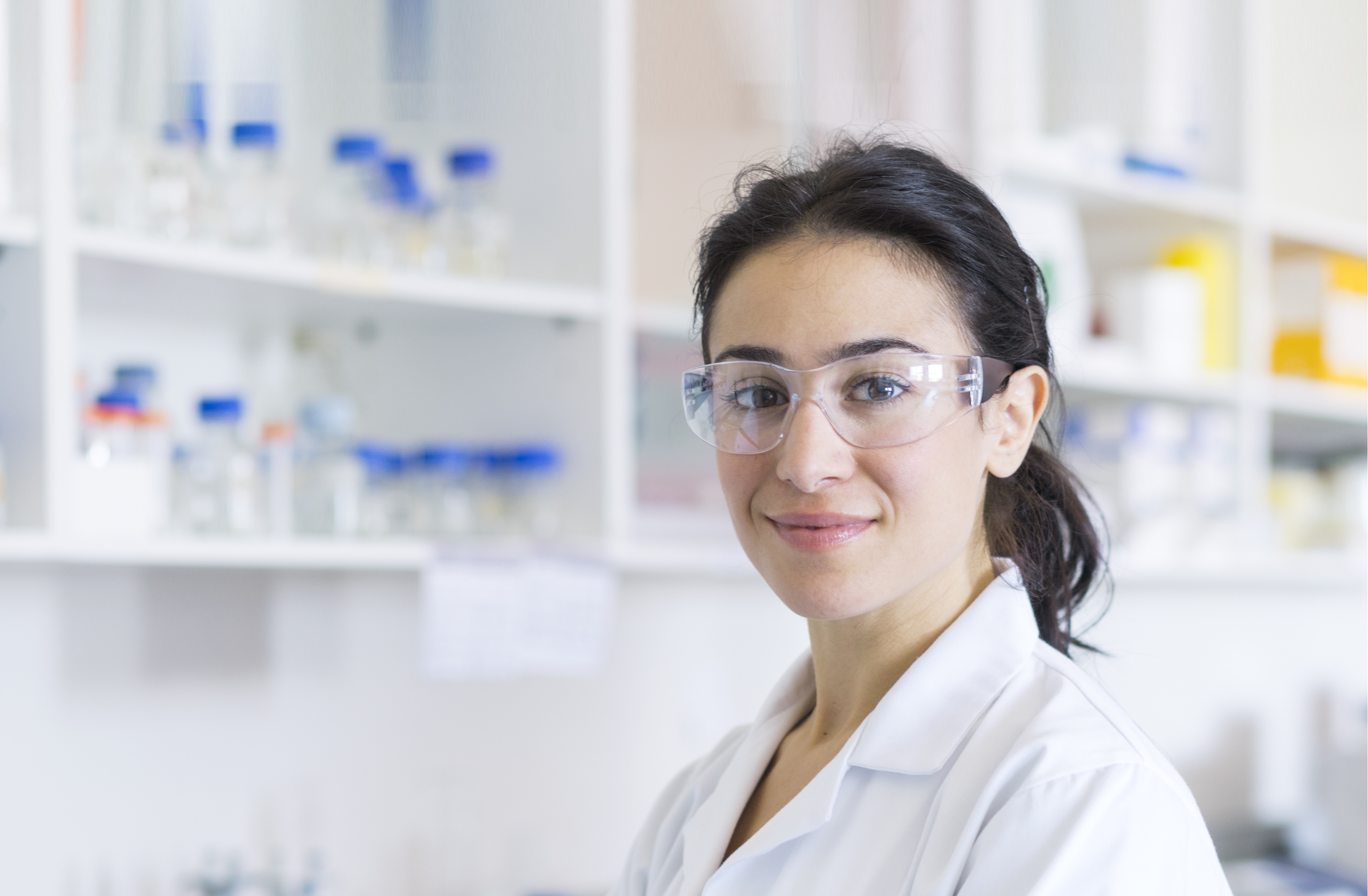 Hero image of woman in white lab coat and protective glasses