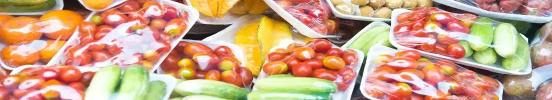 Frutos e vegetais embalados em plástico e dispostos numa prateleira de supermercado