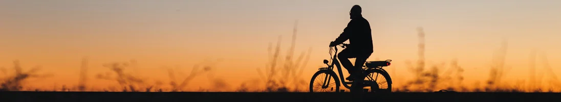 homem a andar de bicileta elétrica ao pôr do sol