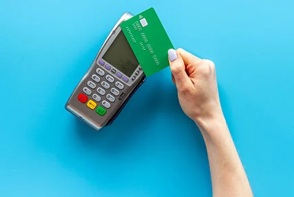 mão com cartão multibanco a fazer pagamento com fundo azul