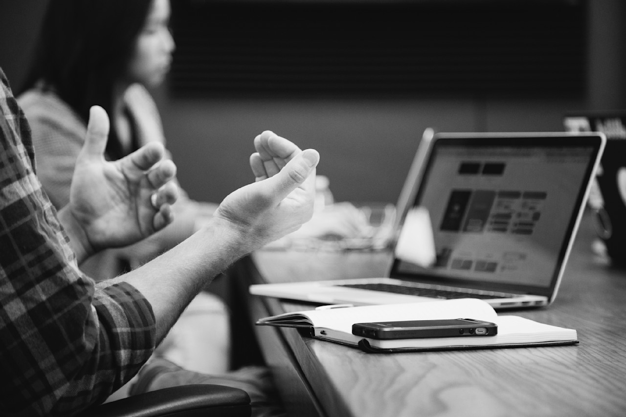 overleggen met collega en laptop & telefoon op tafel headway-5QgIuuBxKwM-unsplash-jaarverslagen-publicaties