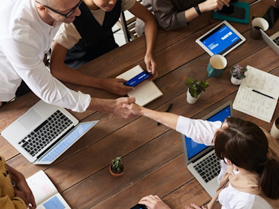 twee mensen om de tafel schudden elkaar de hand samenwerking