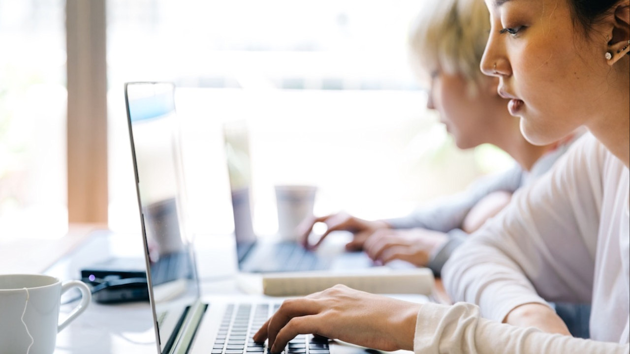 twee vrouwen aan tafel elk achter een eigen laptop zoek de verschillen