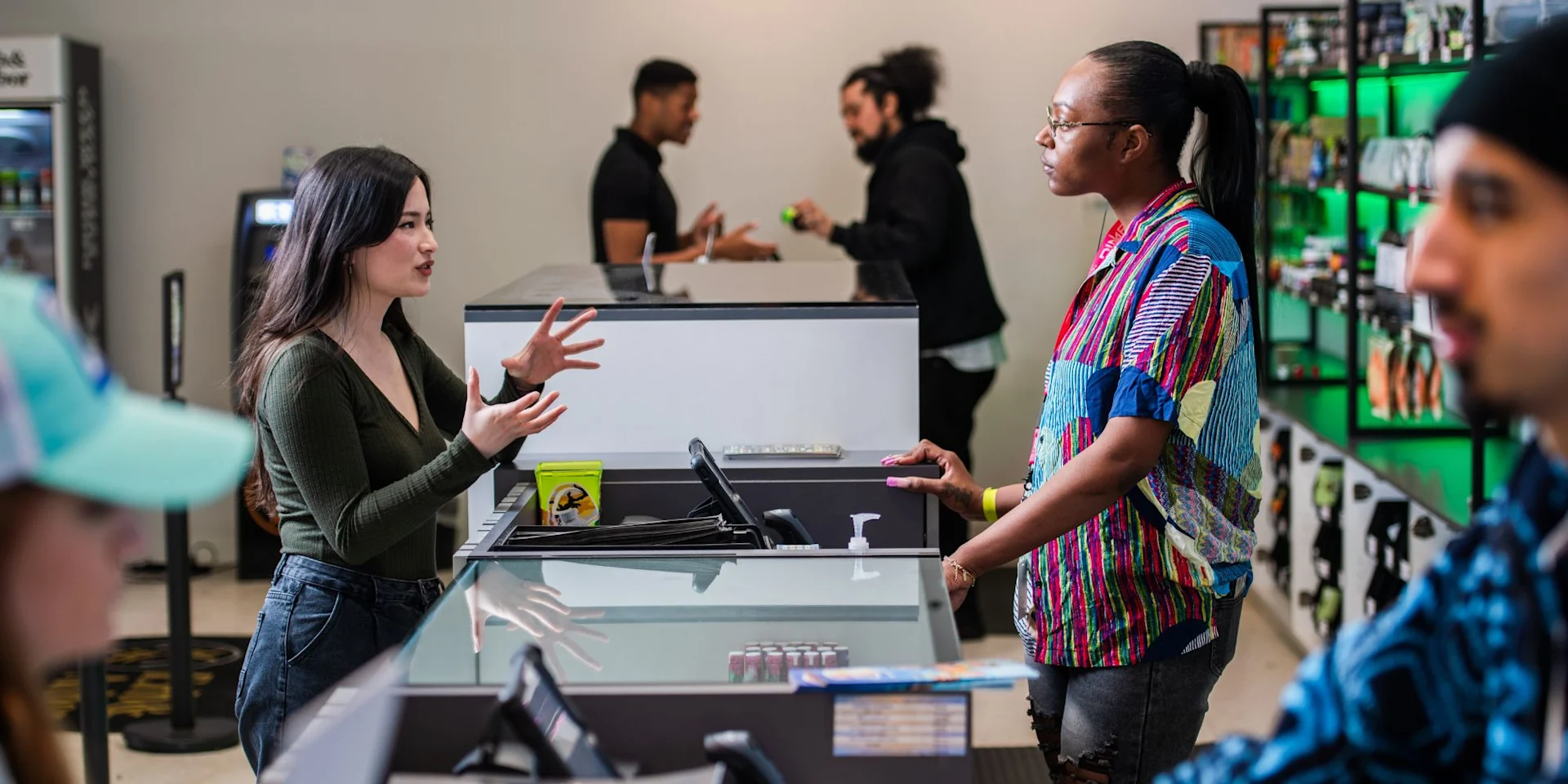 Busy dispensary sales floor with multiple budtenders serving customers at check-out stations