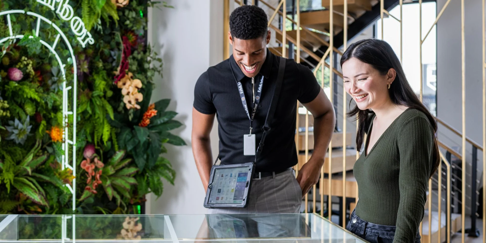 Budtender and customer laughing while reviewing products together on a tablet POS