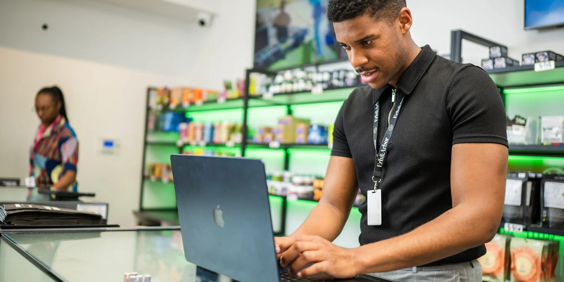 Dispensary staff member working on a laptop at the sales counter behind the display case