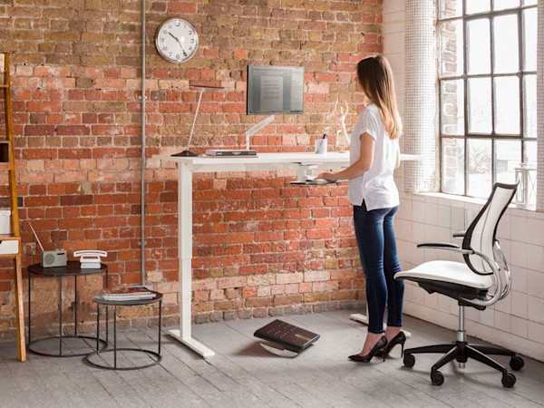 Slender woman standing at sit-stand desk