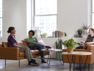 Three women sitting on couch surrounding by plants.