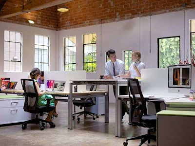 Workers standing and sitting in hybrid workspace.