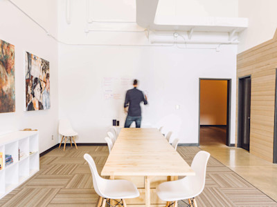 Man facing white board in front of long conference table