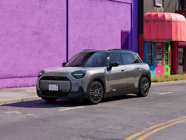 Gray MINI Aceman parked on a street in front of a building with a vibrant purple wall.