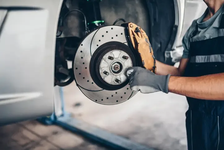 SM | Mecánico revisando disco y pastillas del sistema de frenos de un auto