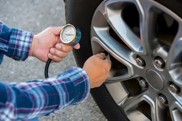 medición de presión de neumáticos con manómetro en rueda de auto