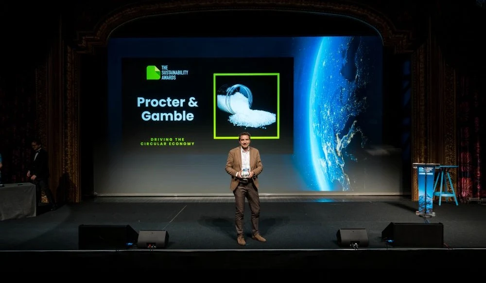 Man speaking at the stage with P&G logo behind