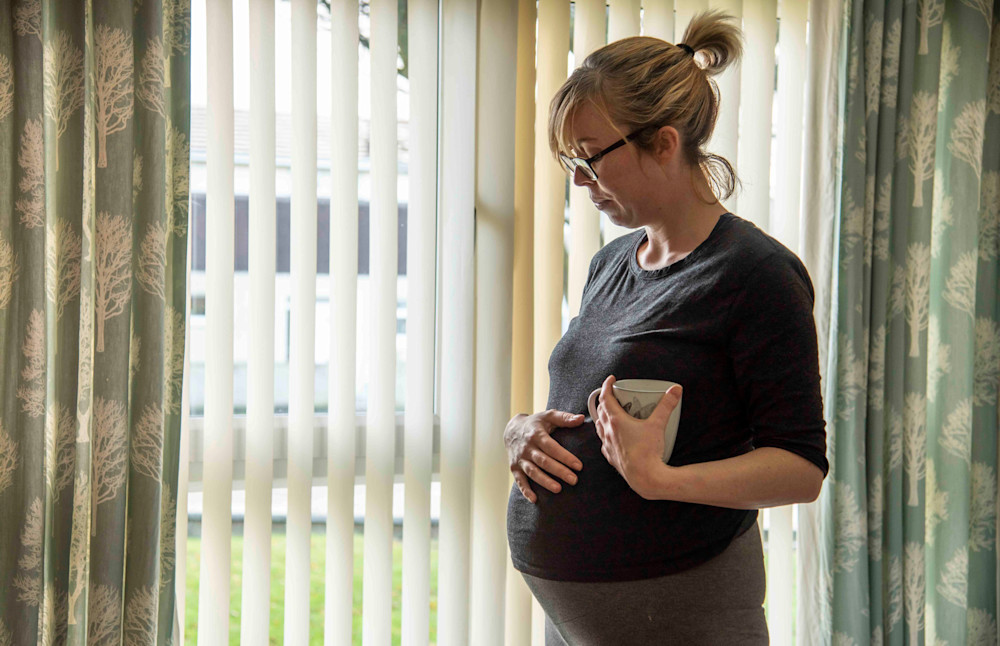 Pregnant woman looking out of window