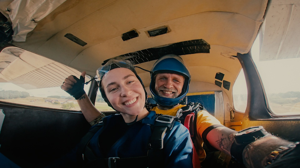 A Shelter Scotland skydive participant takes a selfie in a plane, with her tandem skydiving instructor.