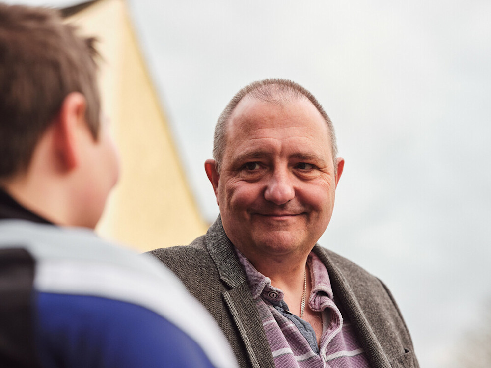 A father smiles while looking at his son.