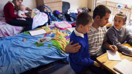 Dad and kids doing homework in overcrowded bedroom