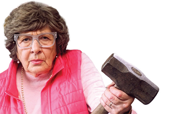 An older woman in pink holding a mallet