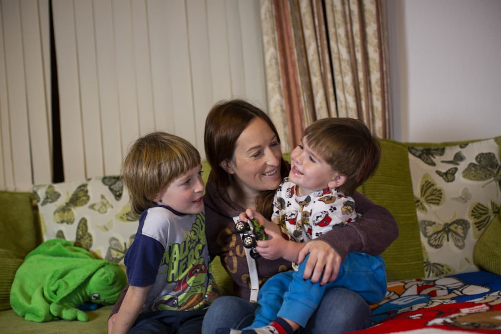 A woman with two boys sitting on a couch