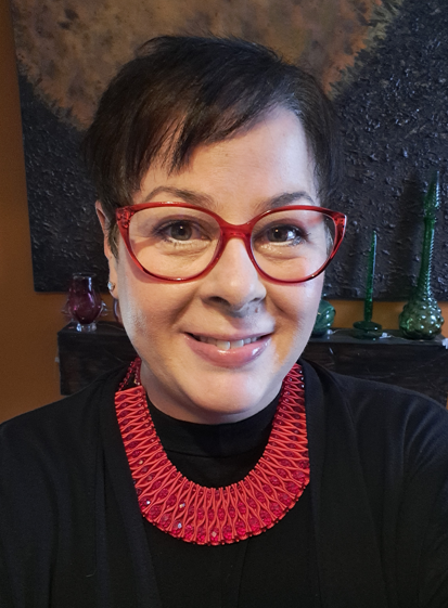 Elena Whitham MSP, wearing a dark top and red spectacles, and a red necklace