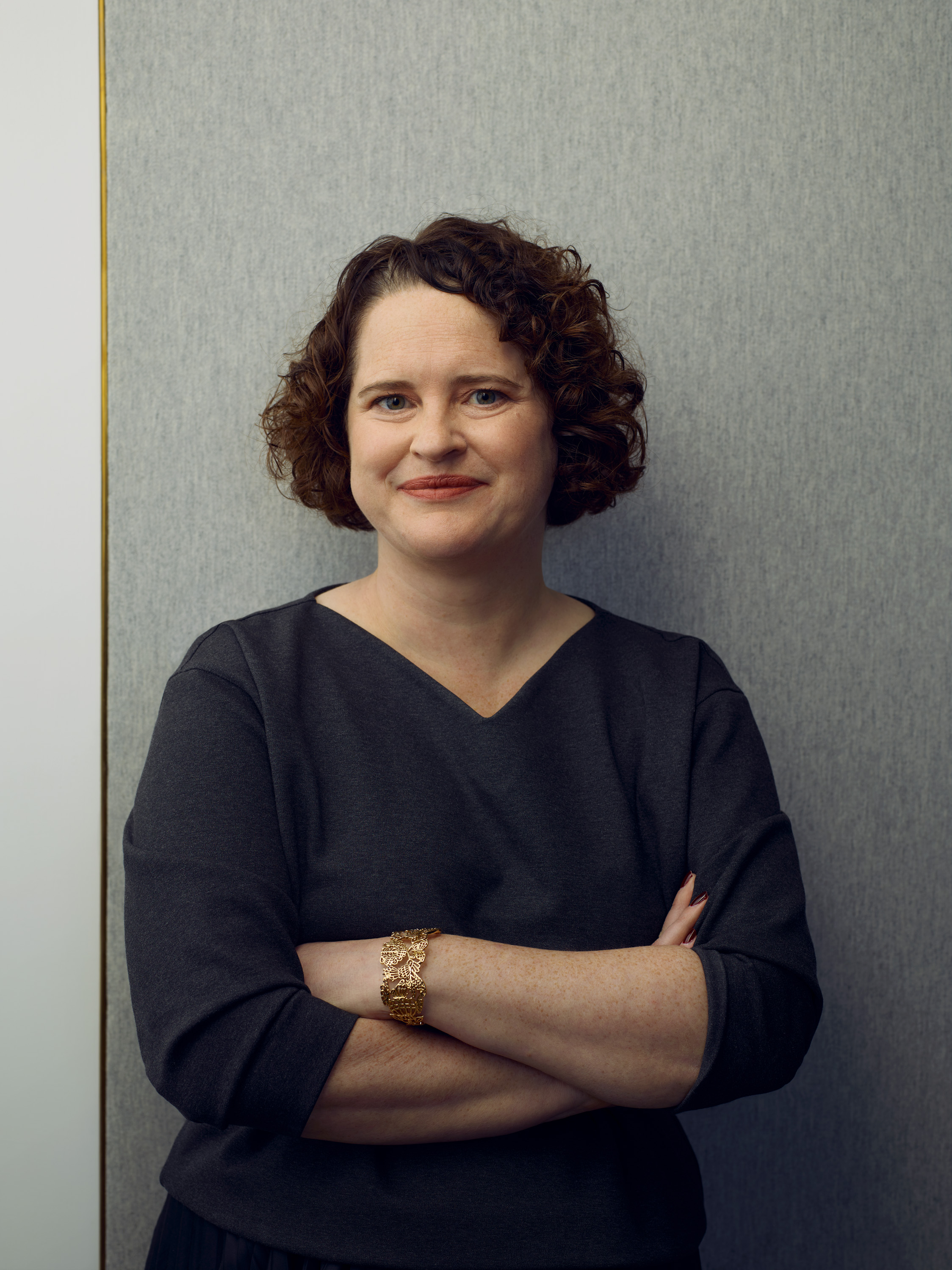 Leonie Foster, a member of Shelter's board of trustees. She has short curly hair and is wearing a black top, smiling at the camera with her arms folded.