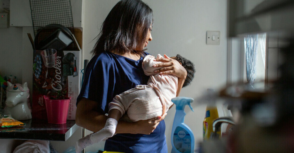 A woman holds her baby in her kitchen