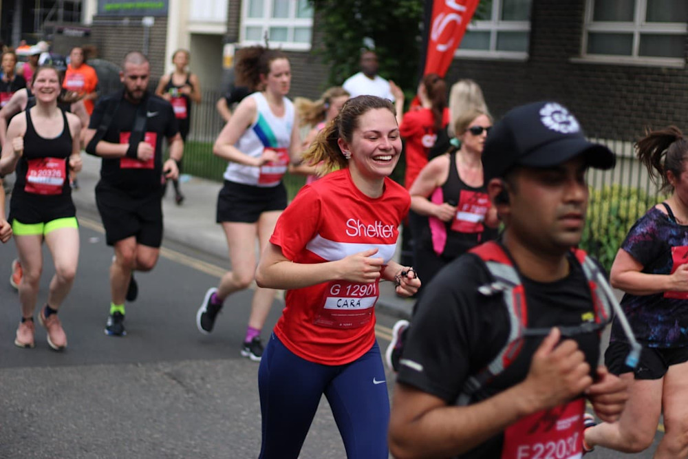 A girl in a Shelter jersey smiling as she takes part in the Virgin Sport Hackney Half Marathon