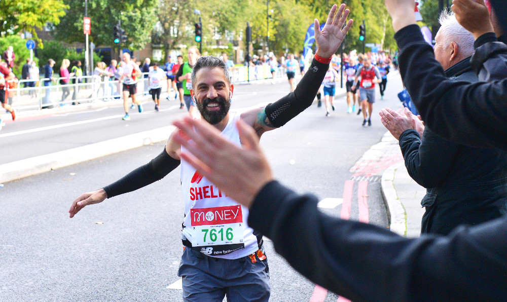 A man in a Shelter jersey smiling as he takes part in the Hackney Half Marathon