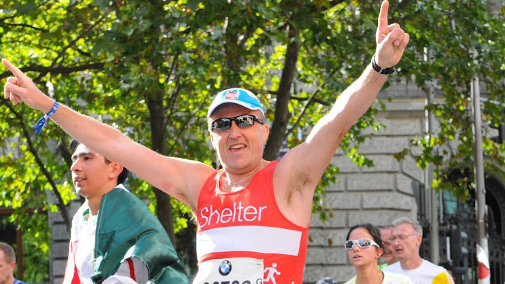 A race runner wearing a Shelter vest and sunglasses in Berlin triumphantly raising his arms