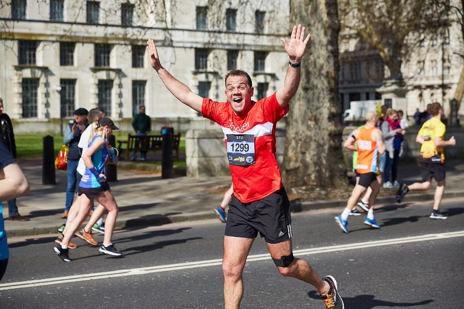 Man running a race on the street with his hands raised