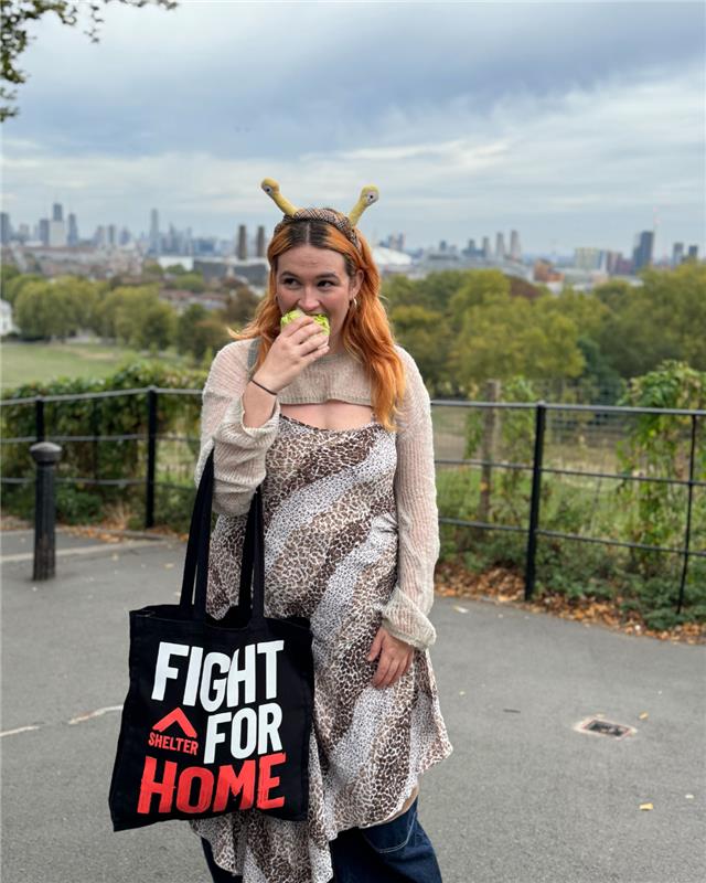 Shelter campaigner dresses as cartoon character 'Shelly The Snail' to highlight the pace of the UK government for the Renters' Rights Bill. She eats a lettuce while wearing a Shelter tote black bag.