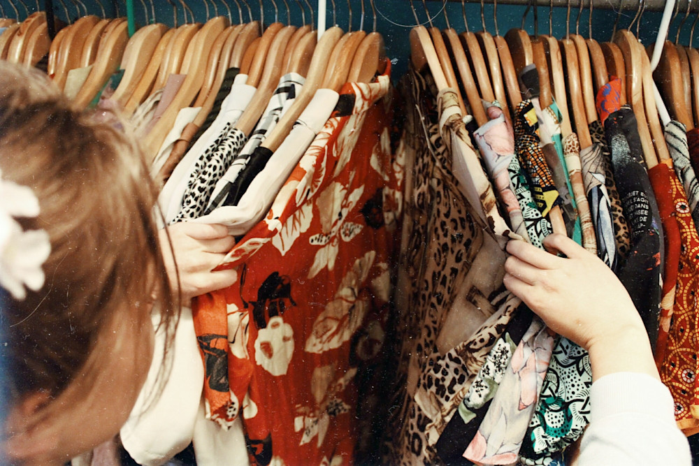 A person ruffling through their clothing rack
