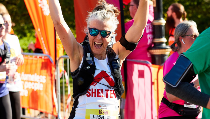 A Shelter Royal Half marathon female runner raises hands whilst smiling into camera