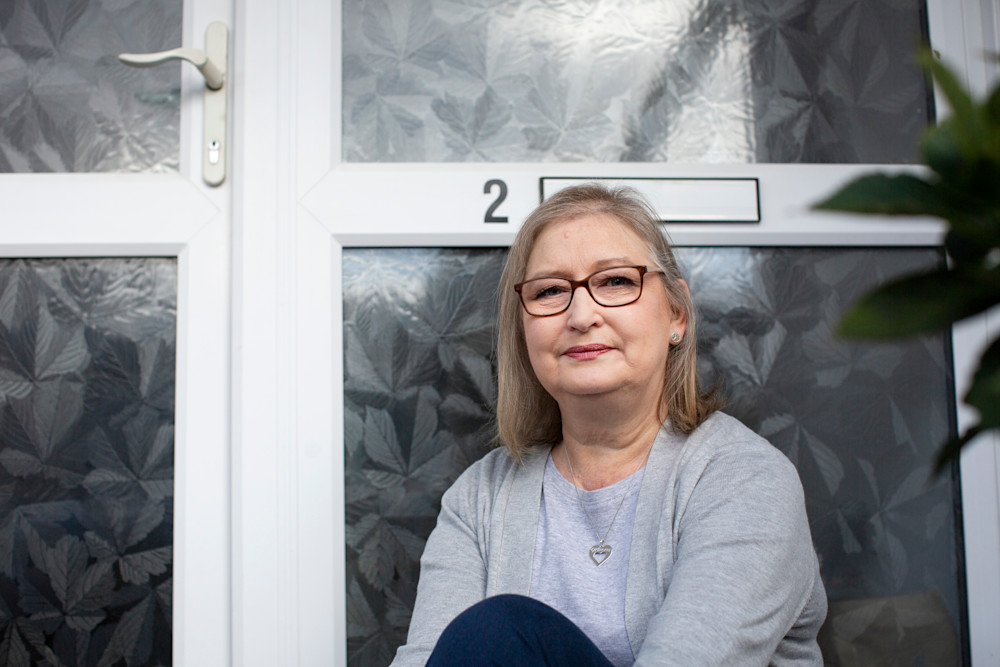 Michelle sits looking thoughtful in front of her front door.