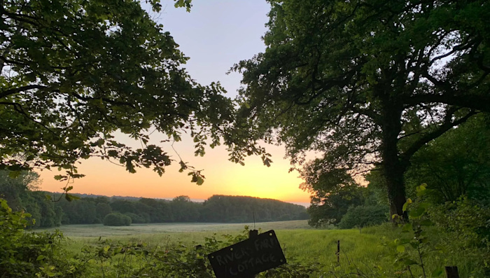 A beautiful sunrise view, with a way marker in the foreground and the coastline in the background.