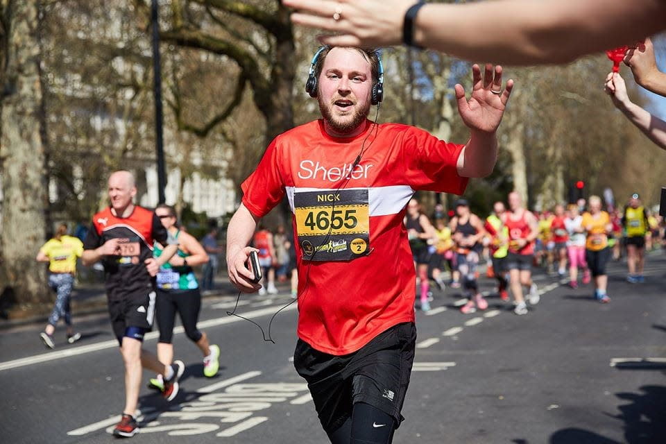 A man in headphones waves as he runs the in the Edinburgh Marathon Festival