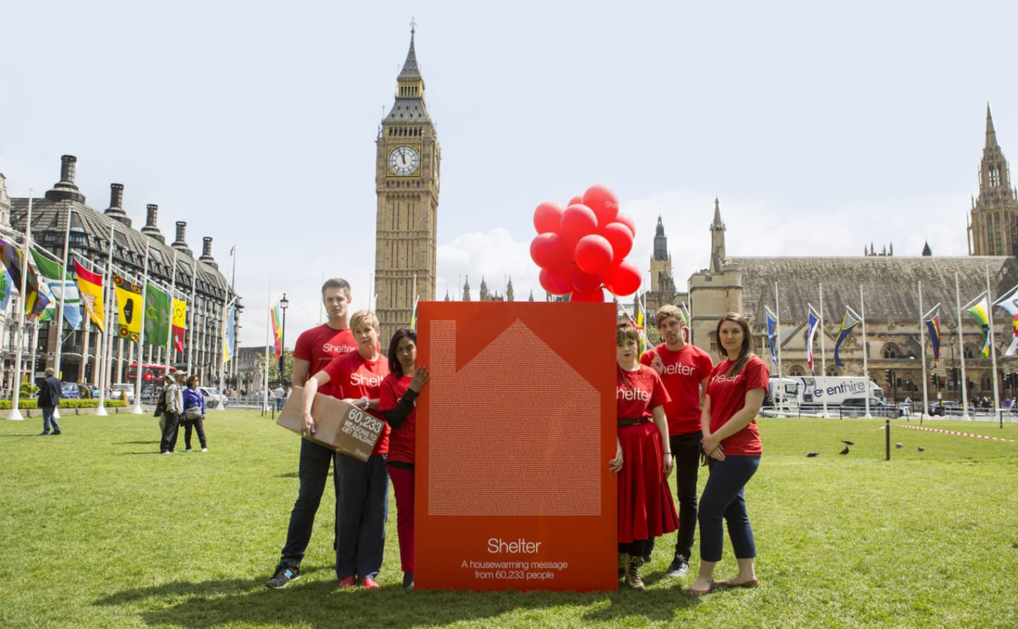 Campaigners outside the Houses of Parliament wearing Shelter t-shirts look into the camera